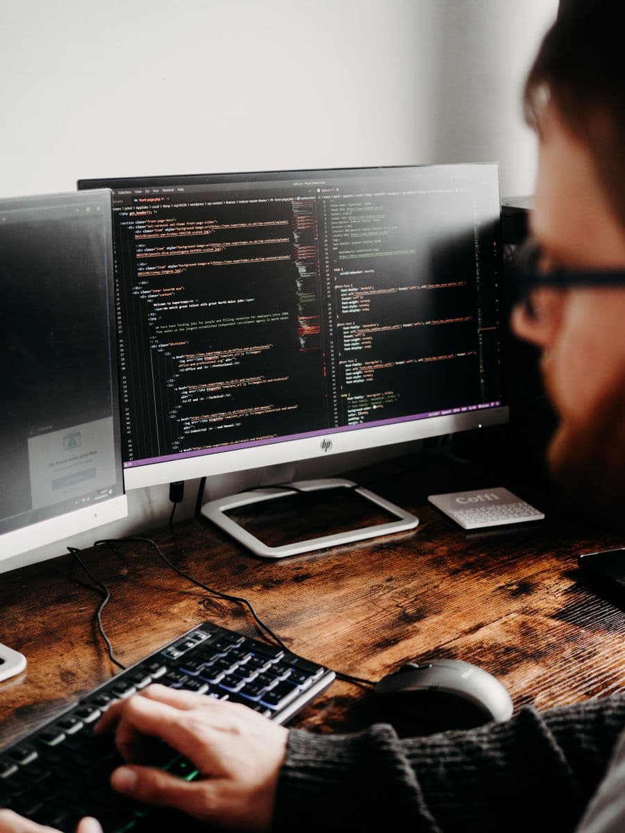 Developer writing code across two monitors