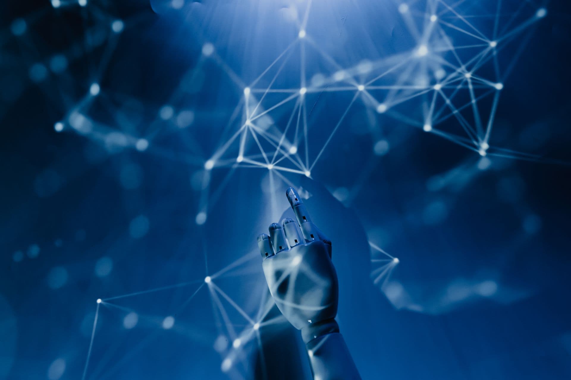 Robotic hand reaching into a glowing blue data network